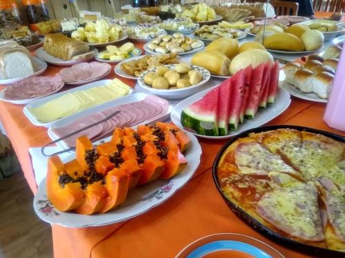 una mesa cubierta con platos de comida y una pizza en Pousada dos Papagaios, en Bom Jardim da Serra