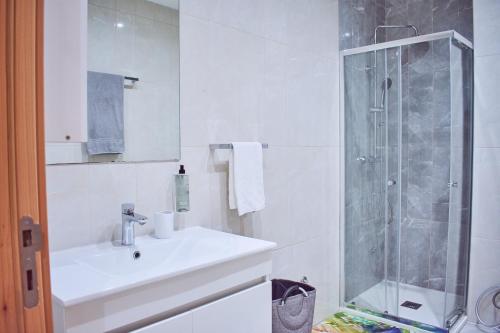 uma casa de banho branca com um lavatório e um chuveiro em Lc Apartments - Sunrise em Santa Maria