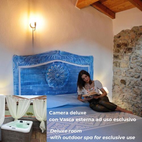a woman sitting on a bed reading a book at Regnos Altos boutique rooms in Bosa