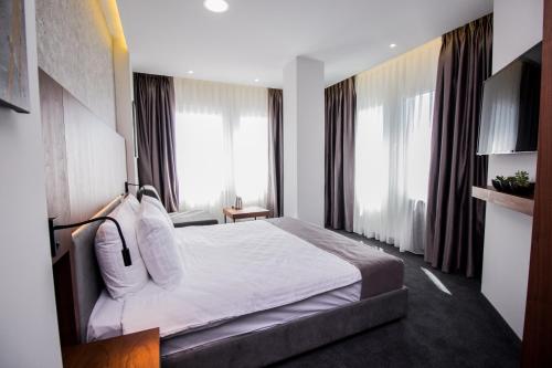a hotel room with a large bed and large windows at Hotel Bograd - Apartments & Lounge Station in Struga
