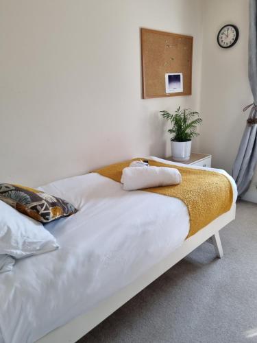 a bed with white sheets and a yellow blanket on it at Deluxe room in a spacious house in Kirby Muxloe