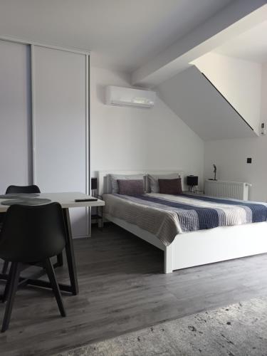 a white bedroom with a bed and a desk at Basztowa Apartament in Świnoujście
