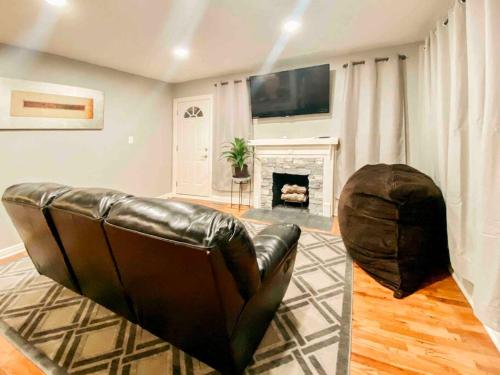 ein Ledersofa im Wohnzimmer mit Kamin in der Unterkunft Charming Farmhouse Retreat near Downtown & University Modern Amenities, Fireplace & Porch! in Birmingham