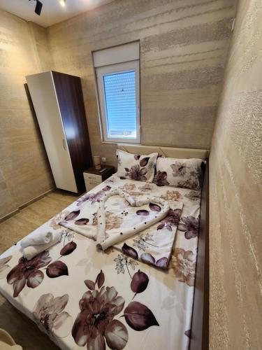 a bedroom with a bed with a floral bedspread at Ebra Lux Apartmani in Dobra Voda