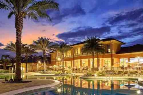 a building with palm trees and a swimming pool at AMAZING vacation house .Mins to Disney Regal oasks in Orlando