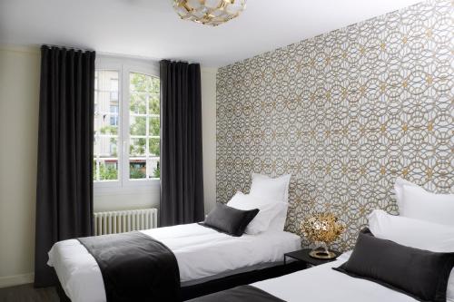 a bedroom with two beds and a wall covered in wallpaper at Les Toits de Chartres - 2 appt - Parking gratuit in Chartres