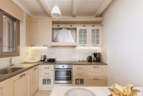 a kitchen with white cabinets and a sink at Stone Pearl Kea in Elliniká