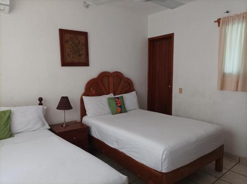 a bedroom with two beds and a lamp on a table at Hotel Villa Tulipanes in Zihuatanejo
