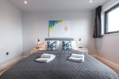 um quarto com uma cama grande e 2 toalhas em Apartment Forty Staines Upon Thames - Free Parking - Heathrow - Thorpe Park em Staines