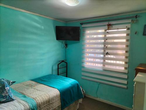 Dormitorio azul con cama y ventana en El hogar de Canela, en Talca