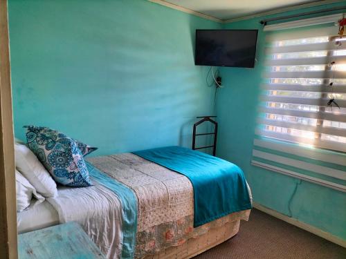 1 dormitorio con 1 cama y TV en la pared en El hogar de Canela, en Talca