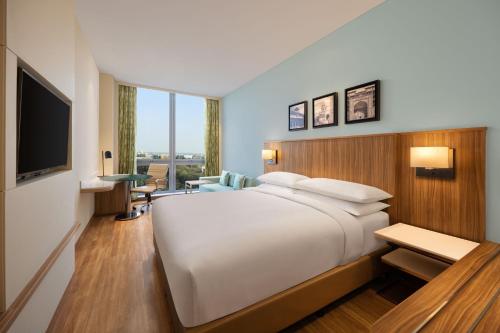 Fairfield by Marriott Agra في آغْرا: غرفة نوم بسرير ابيض كبير وتلفزيون