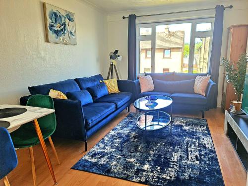 a living room with a blue couch and a table at immaculate 3-Bedrooms Dundee Apartment in Dundee