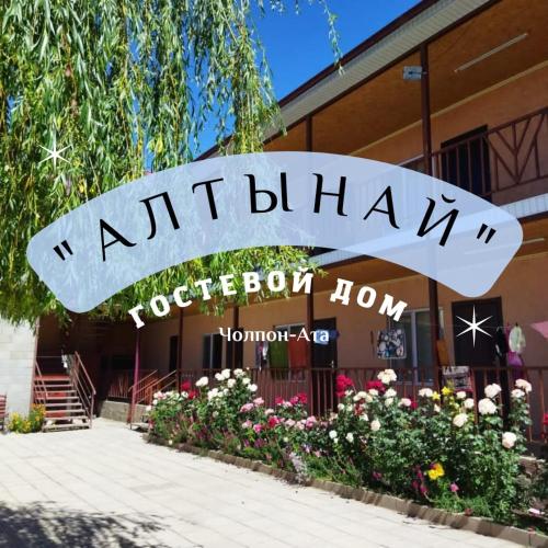a sign for a restaurant with flowers in front of it at AltynAi Guest House in Cholpon-Ata