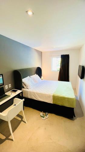 a bedroom with a bed and a desk with a computer at URB Hotel in Fortaleza