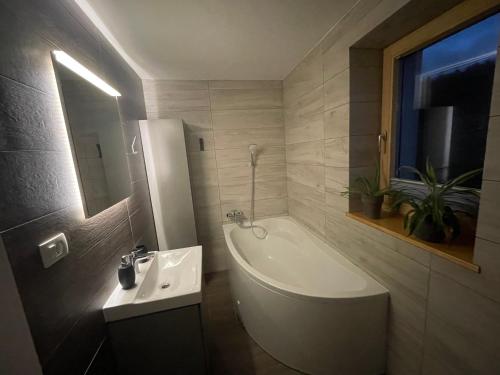y baño con bañera blanca y lavamanos. en Apartma Slatina en Šmartno ob Paki