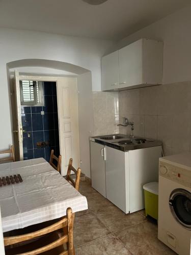 uma cozinha com uma mesa, um lavatório e um fogão em Old Town Apartment em Herceg Novi