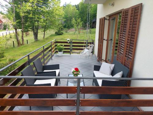 a balcony with chairs and a table and a swing at Holiday Home Čančarević in Ravna Gora