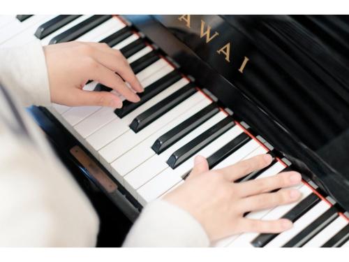 Tottori Guest House Miraie BASE - Vacation STAY 41221v في توتوري: طفل يعزف على لوحة البيانو