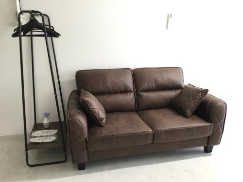 Sofá marrón en la sala de estar con lámpara en Accommodation Service - Vacation STAY 43779v, en Miyazaki