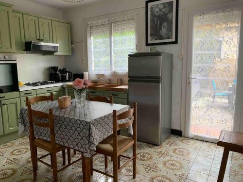 eine Küche mit einem Tisch mit Stühlen und einem Kühlschrank in der Unterkunft Villa le Yucca proche des plages catalanes in Bompas