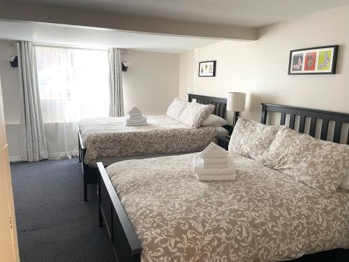 a bedroom with two beds and a couch and a window at Douglas Guest House in Vancouver