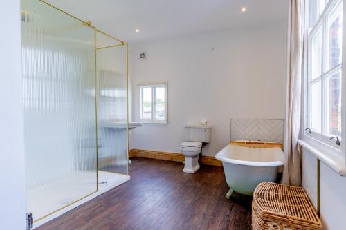 a bathroom with a tub and a toilet and a glass shower at Felicity's House with Hot Tub! 
