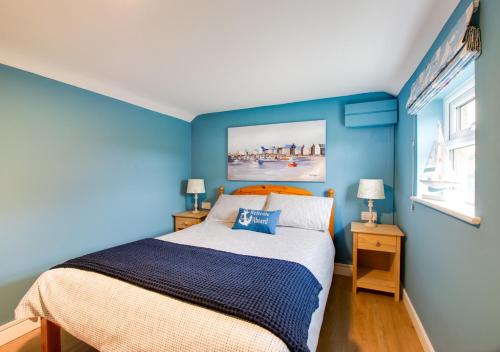 a bedroom with blue walls and a bed and two lamps at Scapa Lodge in Tunstall