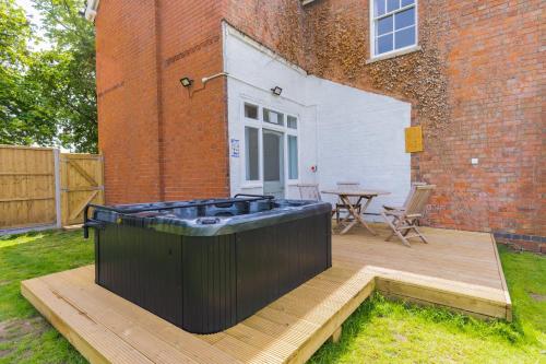 a hot tub sitting on a deck next to a building at Felicity's House with Hot Tub! in Queniborough