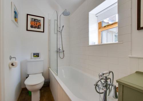 a white bathroom with a toilet and a bath tub at The Nook in Chediston