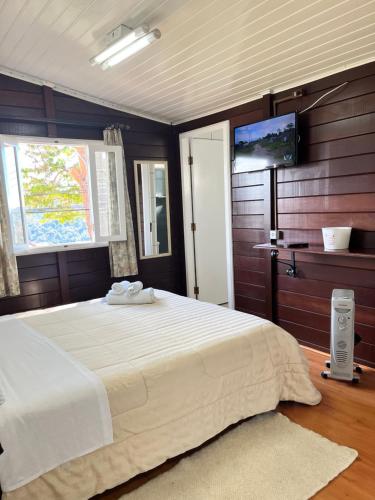 a bedroom with a large bed and a flat screen tv at Pousada do Vento in Campos do Jordão