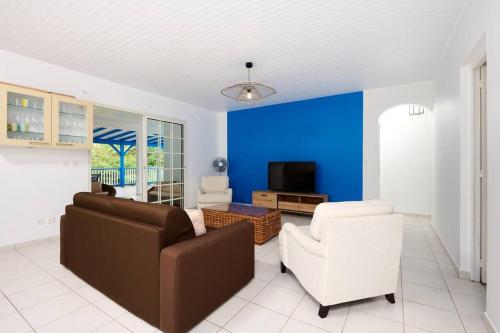 sala de estar con sofá, sillas y pared azul en Villa Pampa, en Sainte-Anne