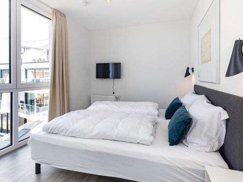 een witte slaapkamer met een bed met witte lakens en blauwe kussens bij Apartment Wendtorf XXVII in Wendtorf