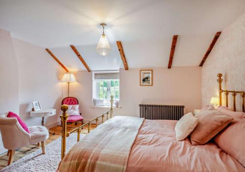 a bedroom with a large bed and a chair at Rose Cottage - Sedgeford in Sedgeford