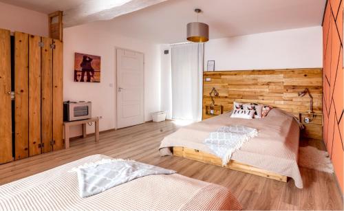 a bedroom with two beds and a wooden wall at Szent György Kúria in Kisharsány