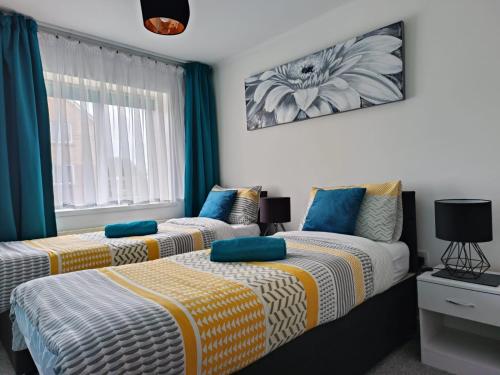 two beds in a room with blue and yellow at Benjamin Gardens Holiday Home in Great Driffield