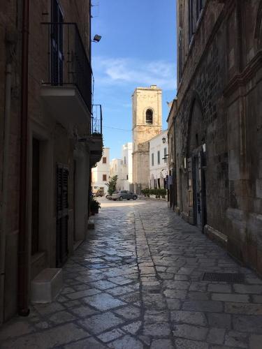 an empty street with a clock tower in the distance at La Casetta 19 in Polignano a Mare