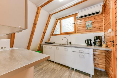 a kitchen with white cabinets and a window at Domki letniskowe Zakątek Kołobrzeg in Kołobrzeg
