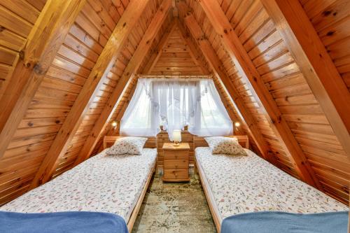 a bedroom with two beds in a wooden house at Domki letniskowe Zakątek Kołobrzeg in Kołobrzeg