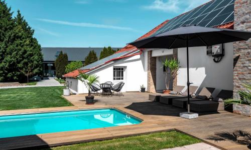 a house with a swimming pool and an umbrella at Szent György Kúria in Kisharsány