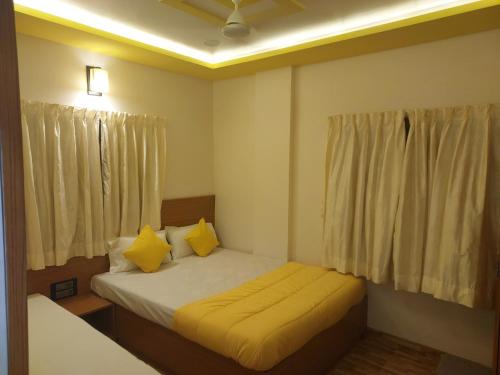 a small bedroom with a bed with yellow pillows at Hotel Sai Dakshina Inn in Shirdi