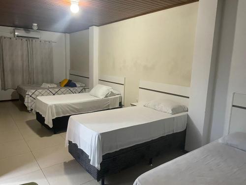 a room with three beds in a room at Central 2 - Pousada in Uruguaiana