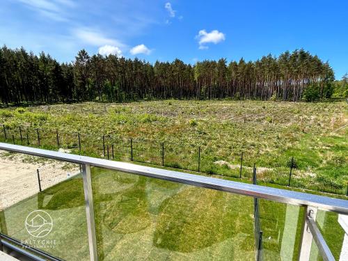 a view of a field from a glass balcony at Apartamenty Bałtyckie - Luxoro Park in Ustka