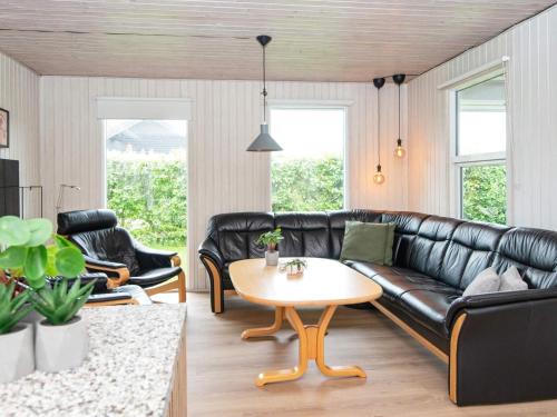 Sønderbyにある9 person holiday home in Juelsmindeのリビングルーム(黒い革張りのソファ、テーブル付)