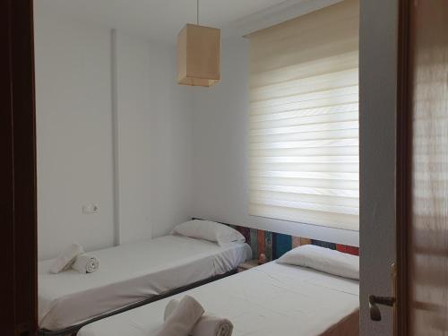 two beds in a room with a window at Luz de sal. Alojamiento, recreo, naturaleza y más! in Lo Pagán