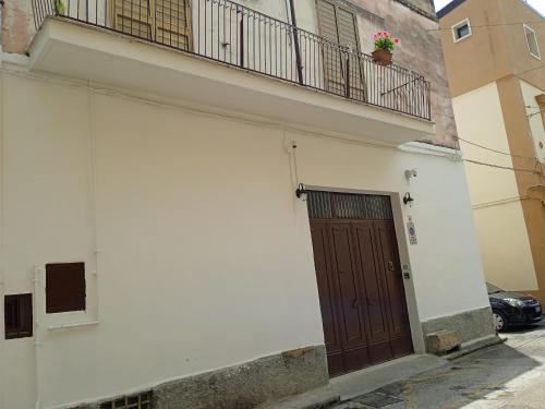 a white building with a brown door and a balcony at B&B La casa dell'ospite in Gravina in Puglia
