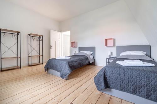 two beds in a room with wooden floors at - WORKERS FAVORITE - Großes Haus mit 8 Einzelbetten und tollem Garten in Wesel