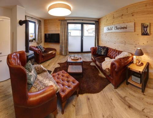 a living room with leather couches and a table at Chalet Charivari Inzell mit Whirlpool, Sauna & Garten in Inzell