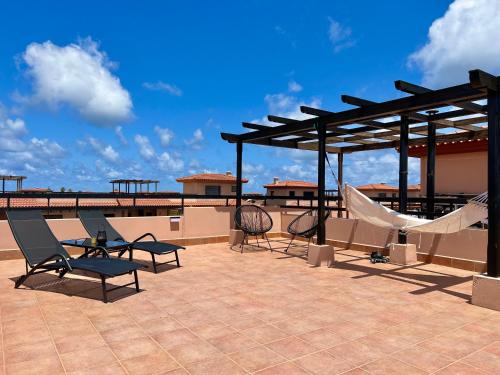 un patio con sillas y una hamaca en la azotea en Villa Aloe, en Lajares