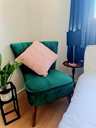 a green chair with a pink pillow in a bedroom at immaculate 3-Bedrooms Dundee Apartment in Dundee